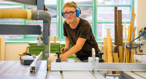 Auszubildender beim Holz sägen